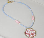 Handmade beaded shell necklace with baby blue beads, pink gemstone accents, freshwater pearls, and gold-trimmed shell pendant, beach jewelry.